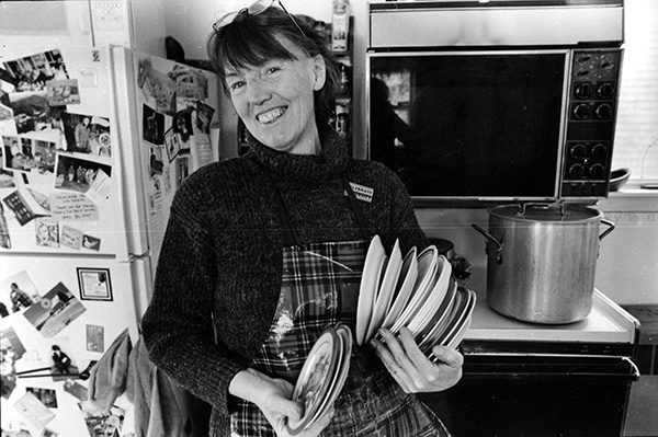 Ruth Ives with a stack of bowls in the kitchen
