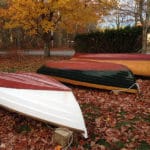 three dinghies stored under fall folliage