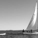 a small sailboat towing a dinghy